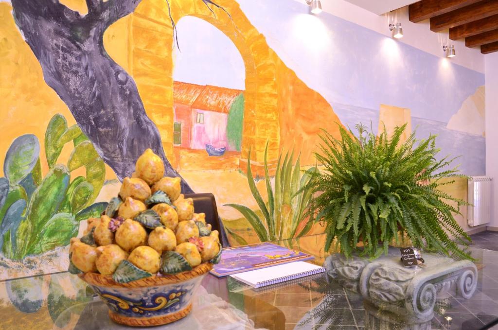una mesa con un bol de fruta delante de un mural en B&B Dimora di Girgenti, en Agrigento
