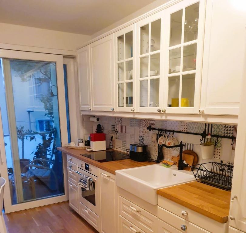 a kitchen with white cabinets and a white sink at Augarten Apartment in Graz