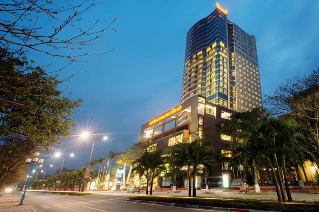 um edifício alto à noite com uma rua em frente em Can ho Muong Thanh em Cửa Lò