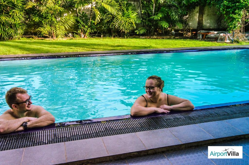 two men laying in a swimming pool at Airport Villa in Katunayaka