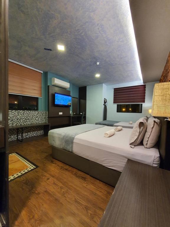 a bedroom with a large bed and a flat screen tv at Cute Hotel & Dorms Ipoh in Ipoh