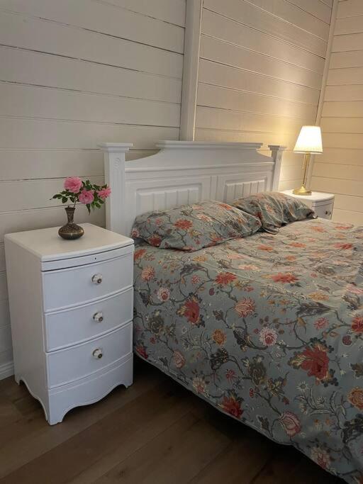 a bedroom with a bed and a nightstand with a flower arrangement on it at Taree CBD cottage apartments in Taree