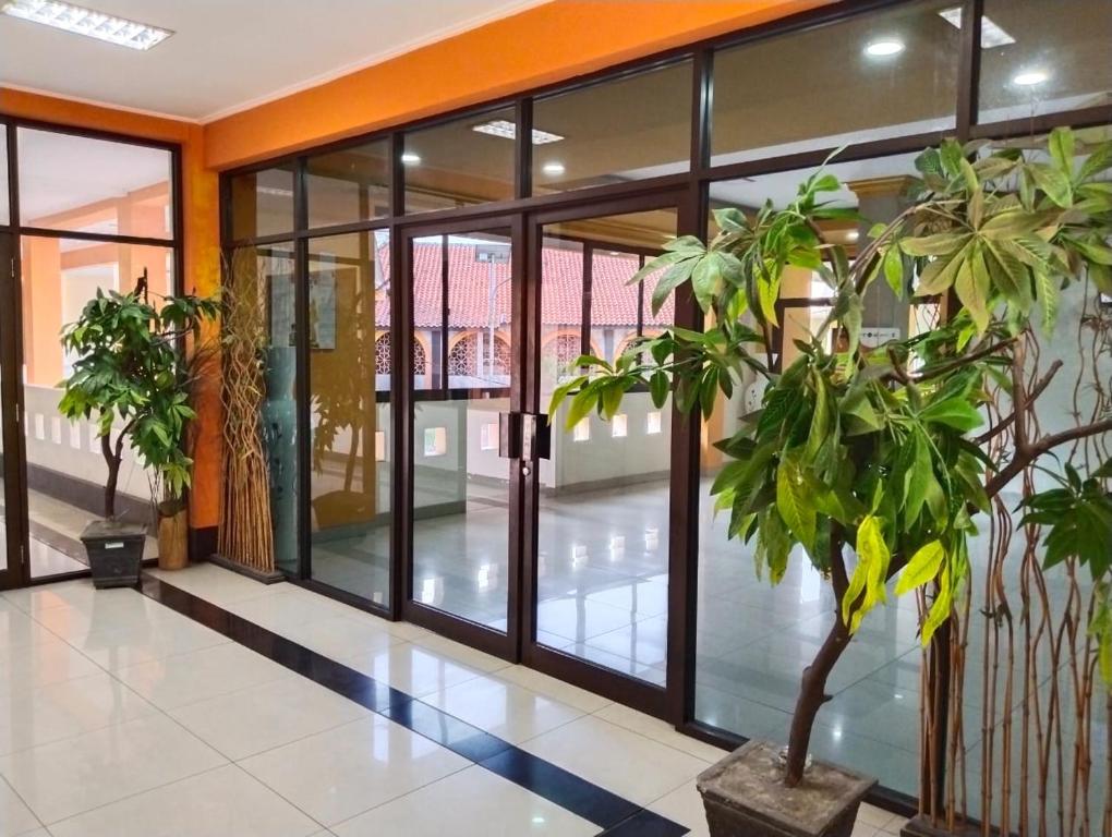 un hall de bureau avec des portes en verre et des plantes en pot dans l'établissement ISLAMIC GUEST HOUSE AT TAQWA, à Cirebon