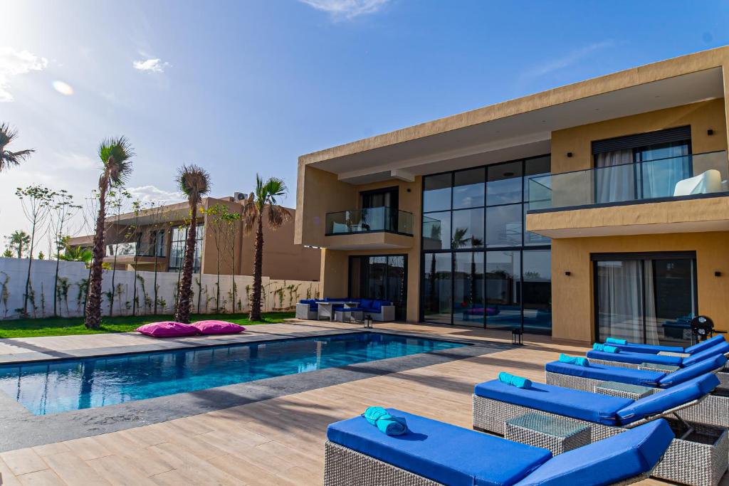 Villa con piscina y tumbonas azules en Villa luxurieuse neuve Jasmin, en Marrakech
