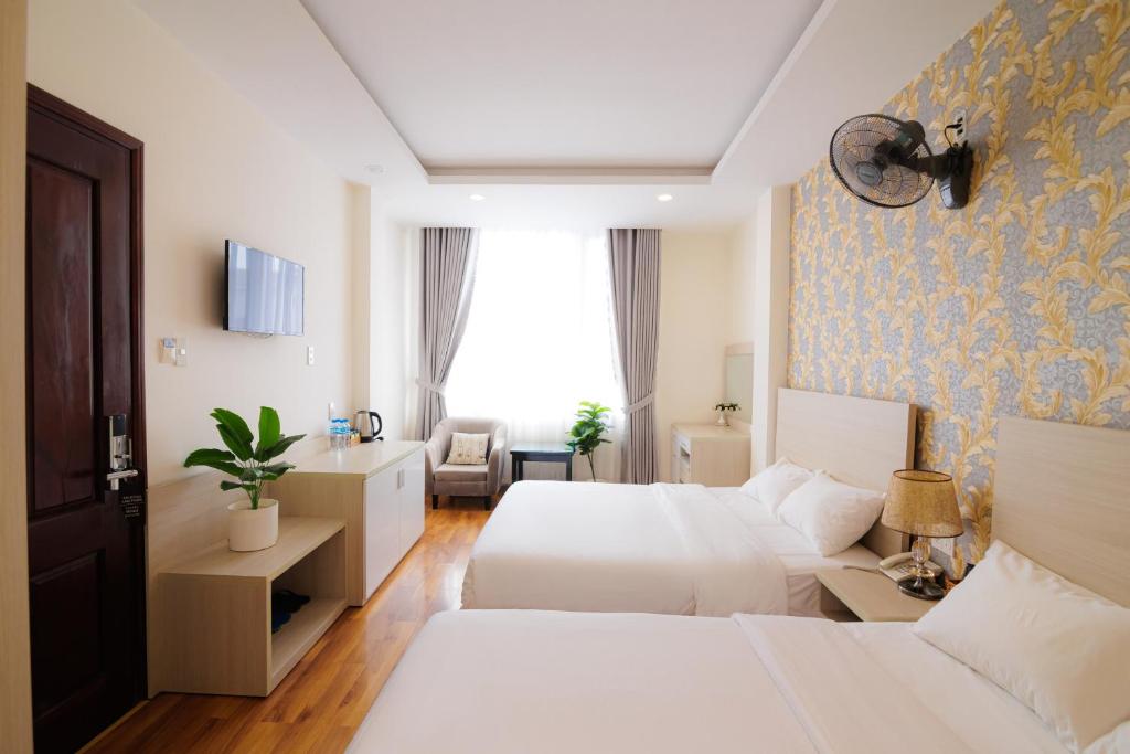 une chambre d'hôtel avec deux lits et un canapé dans l'établissement TTR Vincent Hotel, à Đà Lạt