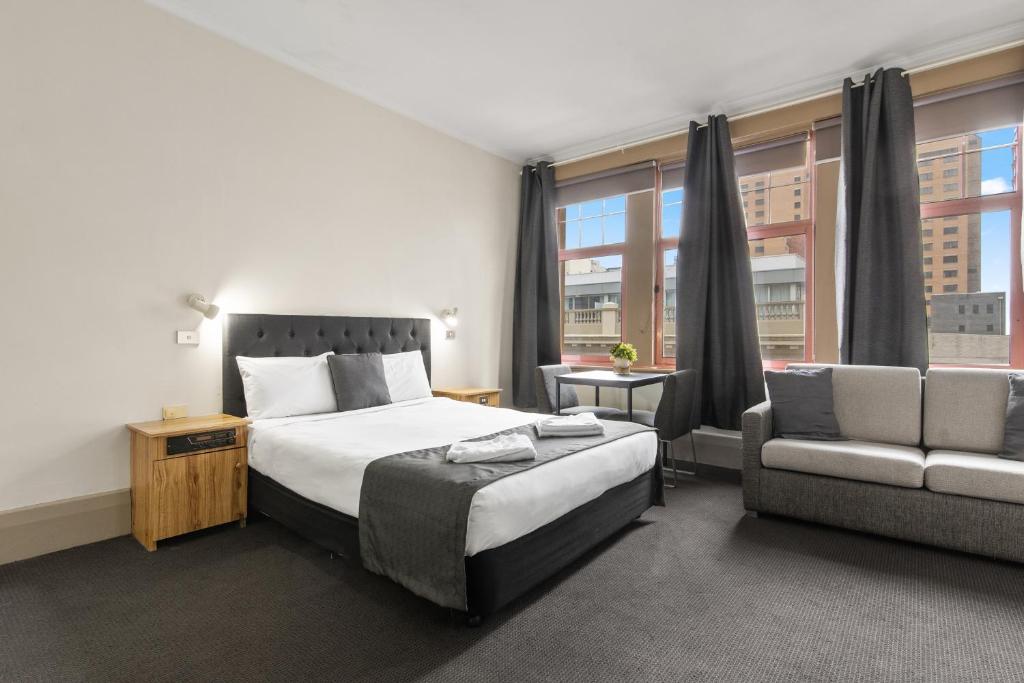 a hotel room with a bed and a couch and window at Adelaide Paringa in Adelaide