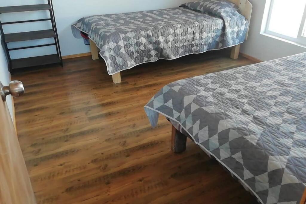 a room with two beds and a wooden floor at casa en la playa in Buchupureo