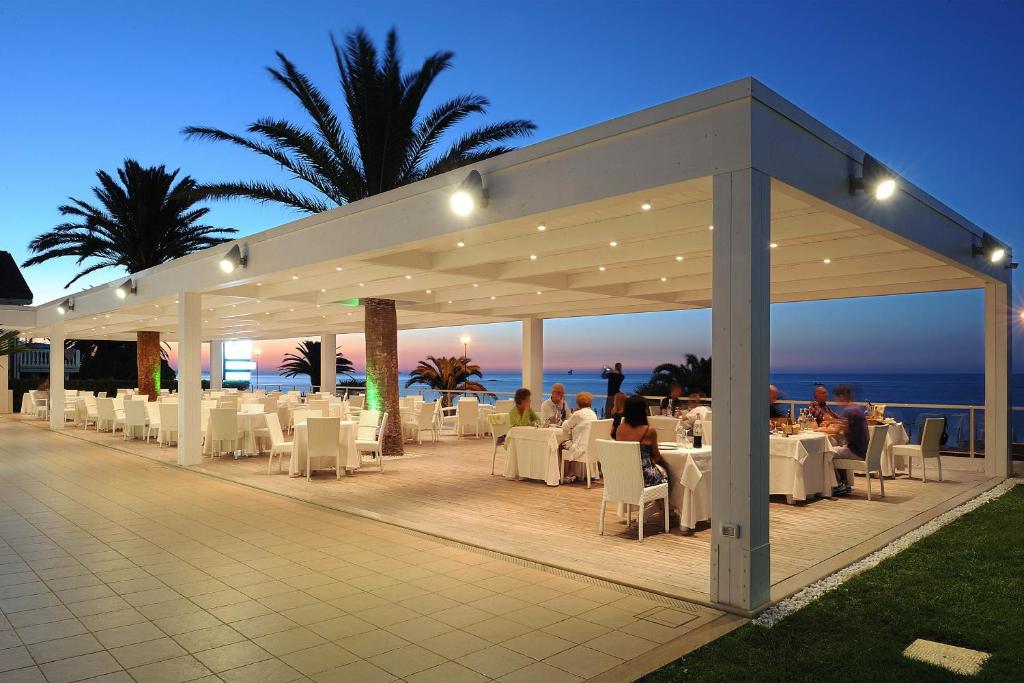 un pabellón con mesas y sillas blancas y el océano en Hotel Sporting, en Casalbordino