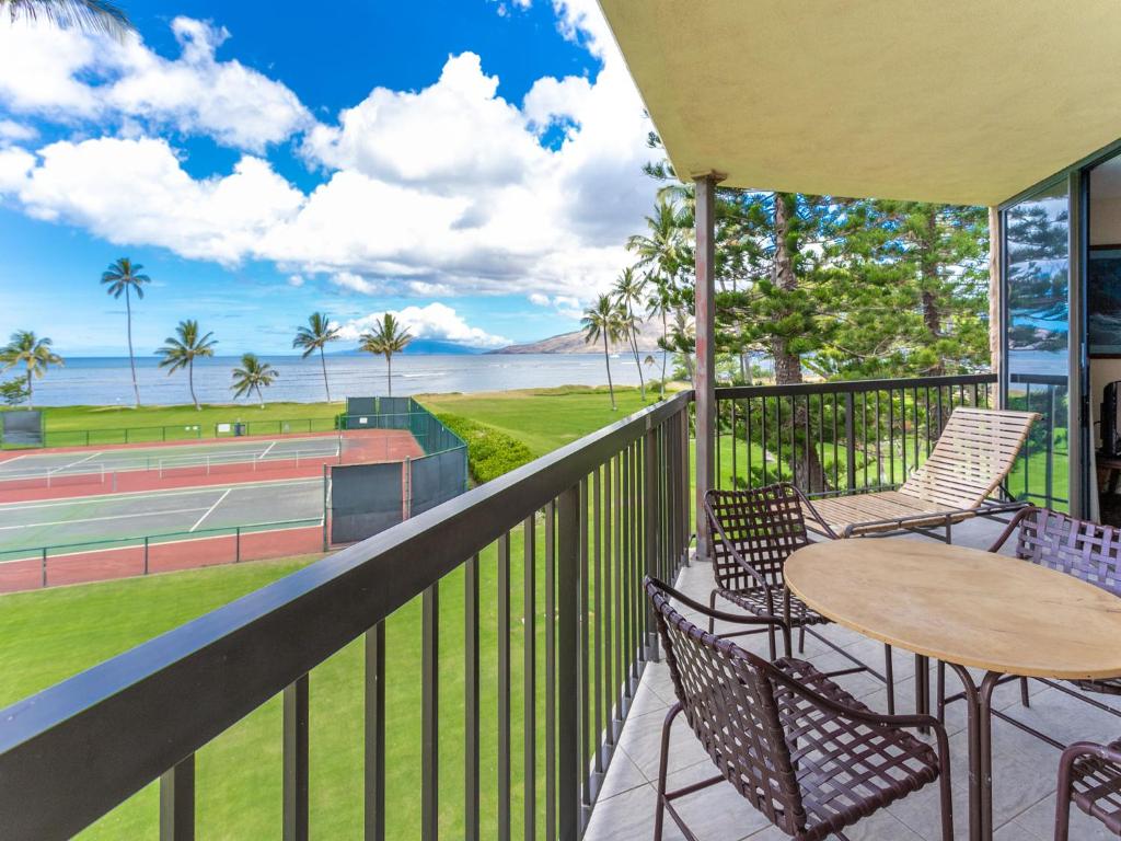 un balcón con mesa y sillas y una pista de tenis. en Maui Sunset A-322, 3 Bedrooms, Ocean View, Pool, Tennis, Sleeps 8, en Kihei