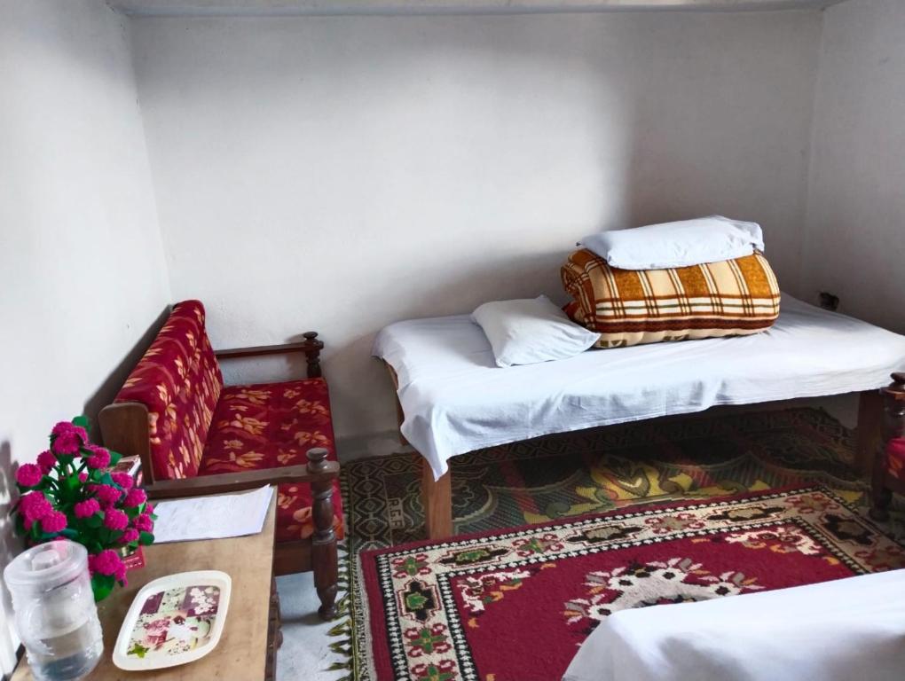 um quarto com duas camas e uma cadeira e uma mesa em Shradha Homestay Leeti em Bāgeshwar