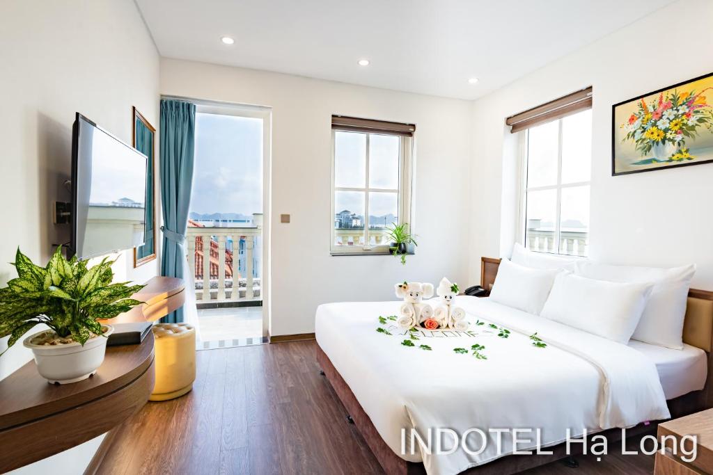 a bedroom with a large white bed and windows at INDOTEL HALONG HOTEL in Ha Long