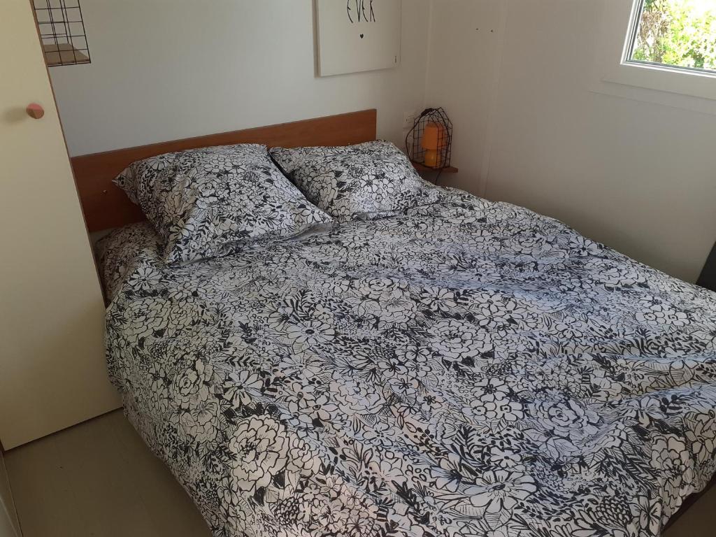 a bed with a blue and white comforter and pillows at MH 4 personnes 5 étoiles plages du debarquement in Sainte-Mère-Église
