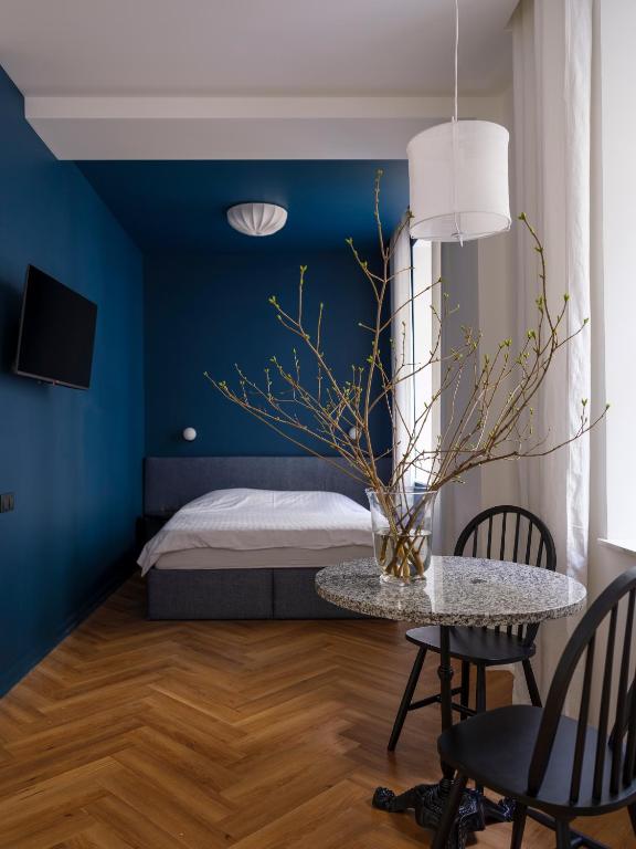 a bedroom with blue walls and a table with chairs at MIRO Rooms Skolas - quiet chic, free parking, self check-in in Rīga