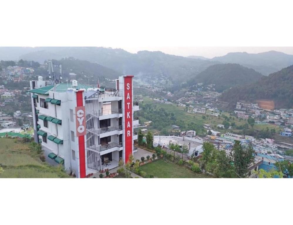 a building with a sign in front of a city at Hotel Satkar, Pithoragarh in Pithorāgarh