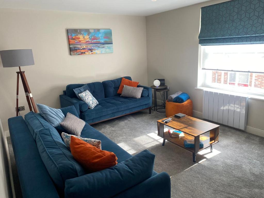a living room with two blue couches and a table at RECENTLY RENOVATED property in the heart of Southwell in Southwell