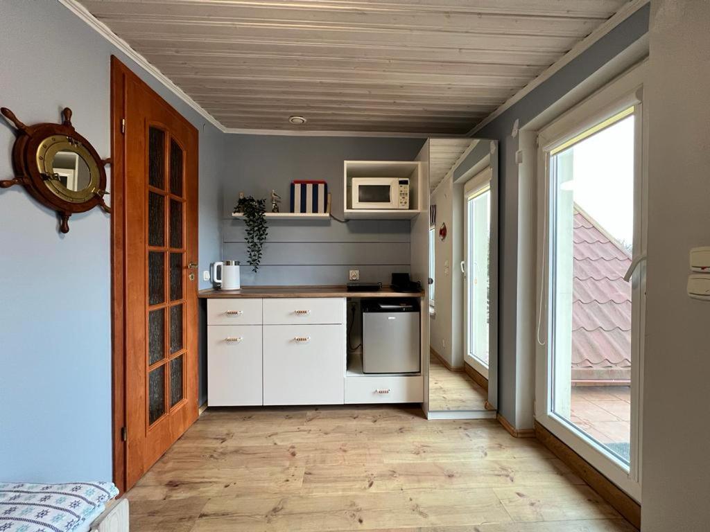 a kitchen with white cabinets and a microwave at Pokój 2-osobowy z balkonem in Gdańsk