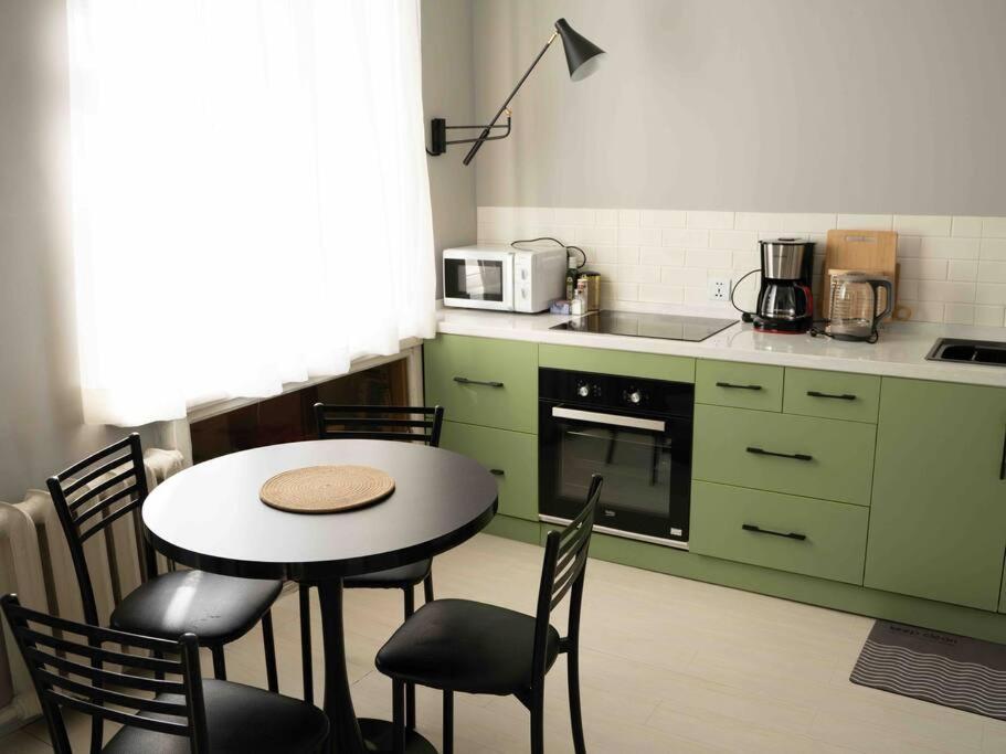 eine Küche mit einem Tisch, Stühlen und einer Mikrowelle in der Unterkunft Comfy apartment in the heart of Ulaanbaatar in Ulaanbaatar