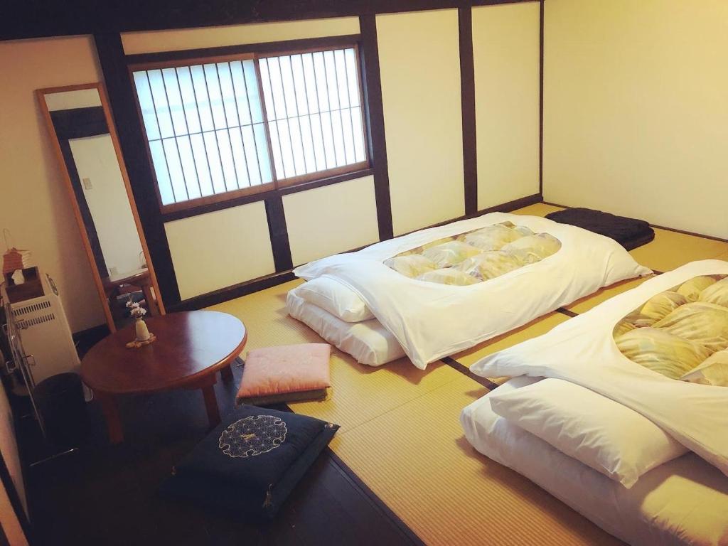 two beds in a room with a table and window at Tanekura Inn 