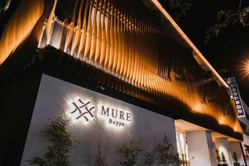 un panneau sur le côté d'un bâtiment la nuit dans l'établissement MURE Beppu, à Beppu