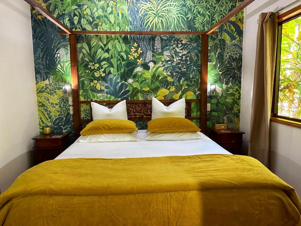 um quarto com uma cama grande com lençóis amarelos em Crater Lakes Rainforest Cottages em Yungaburra