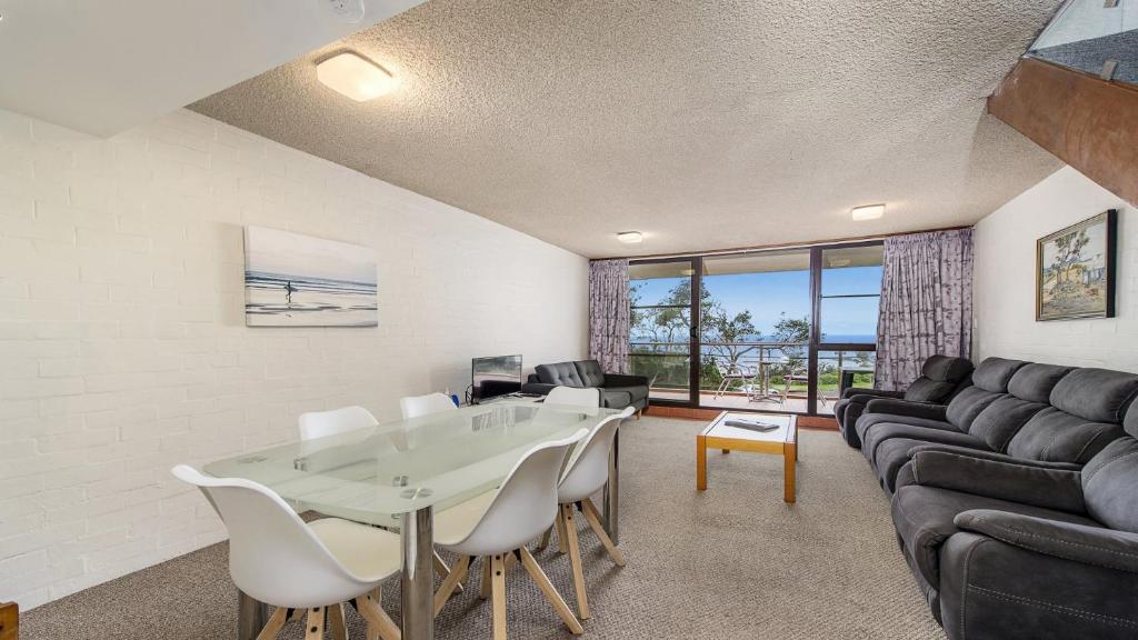 uma sala de estar com uma mesa e um sofá em 60 Beachpark Apartments - 58 Pacific Drive em Port Macquarie