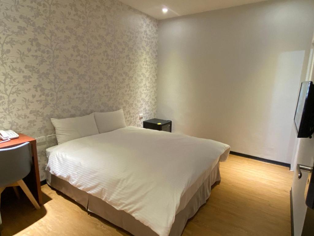 a bedroom with a white bed and a television at The Prince Hotel in Tainan