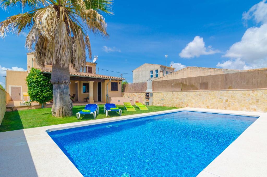 a swimming pool in front of a house with a palm tree at Carles in Vilafranca de Bonany