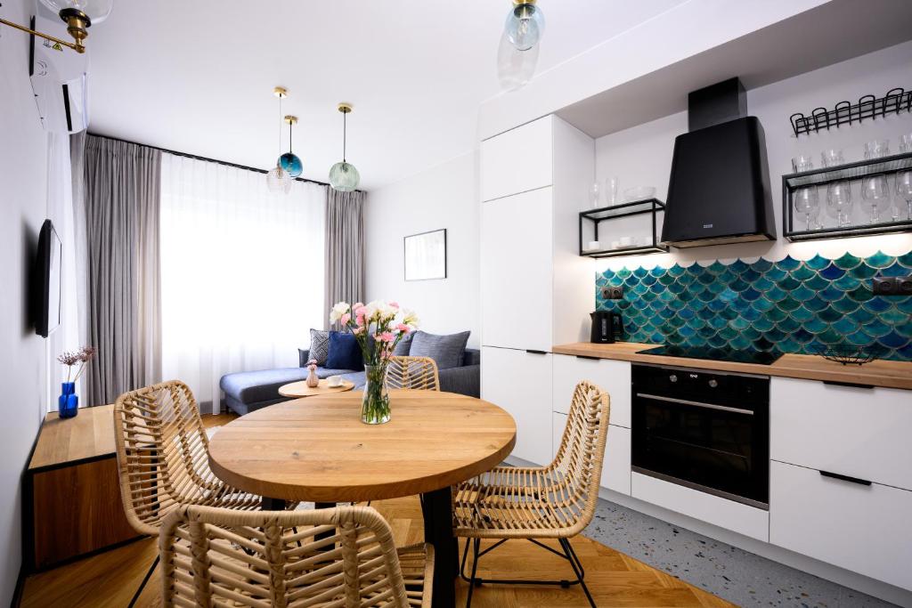 a kitchen and dining room with a wooden table and chairs at Native Apartments Barska 69 in Krakow