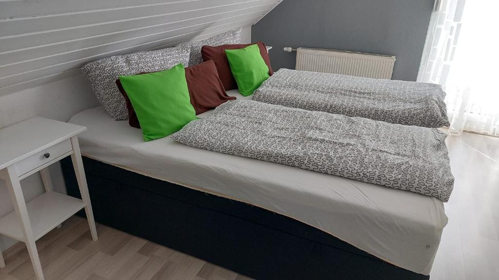 a bed with green and grey pillows and a table at Gästehaus Yvonne Sigg in Rust