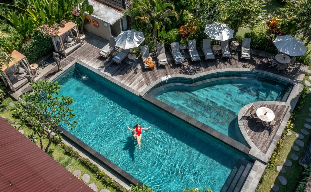 een uitzicht op een persoon die in een zwembad zwemt bij Kailash Suites by Pramana Villas in Ubud