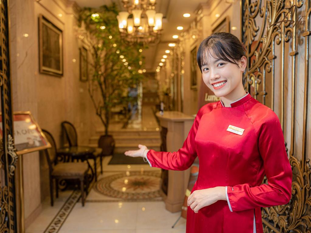 Una mujer con un vestido rojo parada en un pasillo en Affa Boutique Hotel en Hanoi
