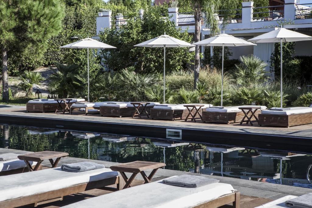 a pool with tables and chairs and umbrellas at La Suite Boutique Hotel in Procida