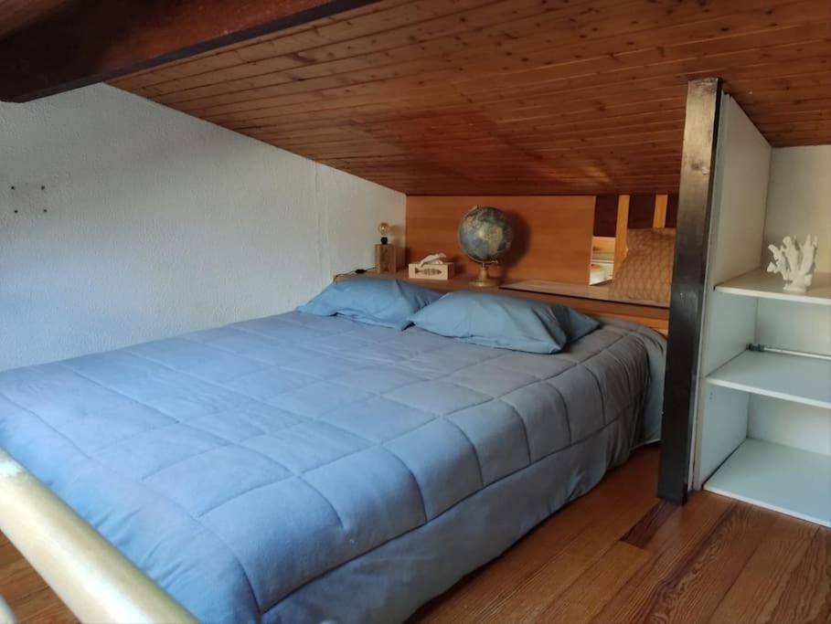 a bedroom with a blue bed with a wooden ceiling at Studio maubuisson lac/océan 4/6 personnes in Carcans