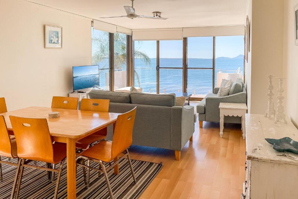a living room with a table and a couch at Harbourside 13 fantastic waterfront unit in Soldiers Point