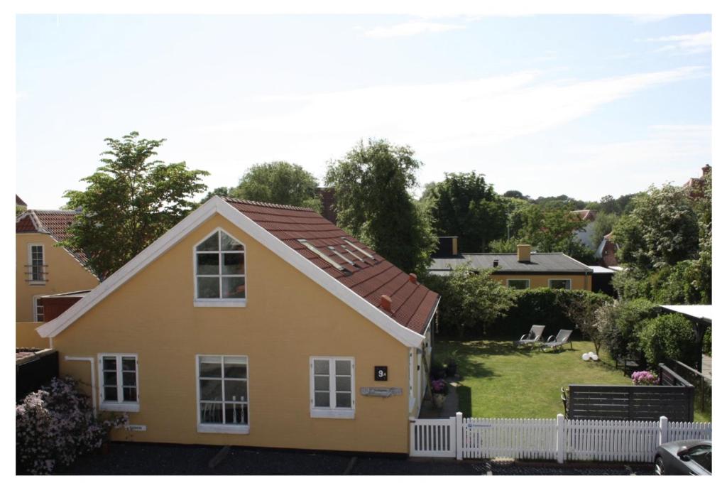 a yellow house with a white fence and a yard at Holiday-Skagen in Skagen