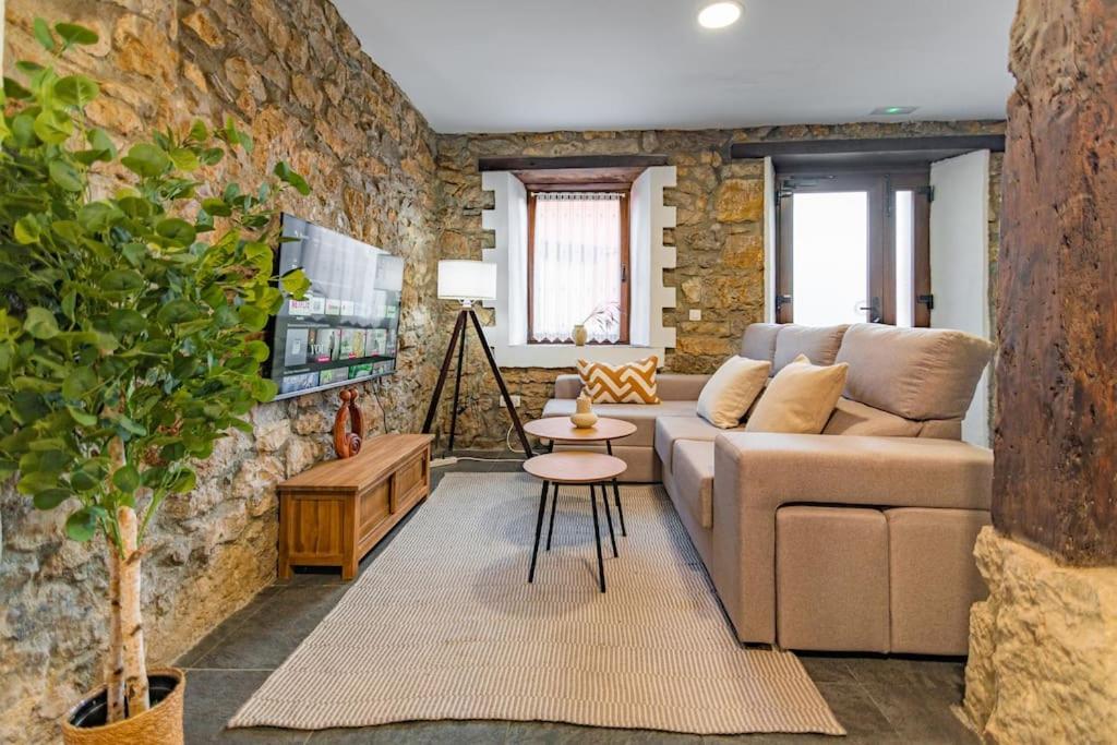 un soggiorno con divano e muro di mattoni di Precioso piso estilo rústico a 10 min de Santander a Camargo