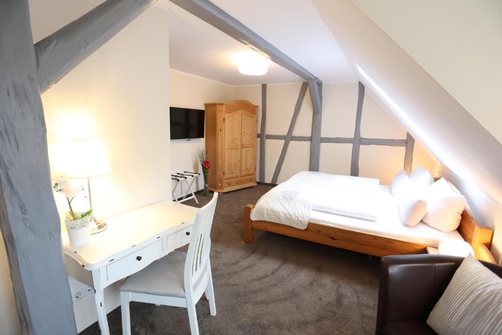 a bedroom with a bed and a desk and a table at Pension Alte Scheune in Melsungen