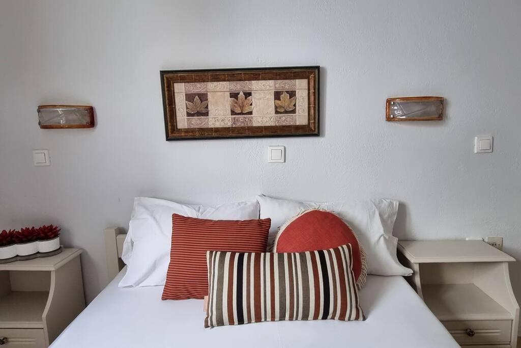 ein weißes Bett mit Kissen und einem Bild an der Wand in der Unterkunft Aspartia in Naxos Chora