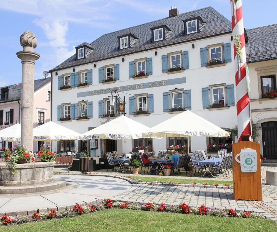 ビショフスグリュンにあるGasthof Deutscher Adler und Hotel Puchtlerの建物の前にテーブルと椅子があるホテル