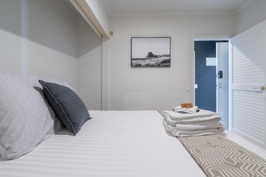 a white bedroom with a bed and a door at Luxury Apartment - Parking - Hot Tub - Stunning Views in Auckland