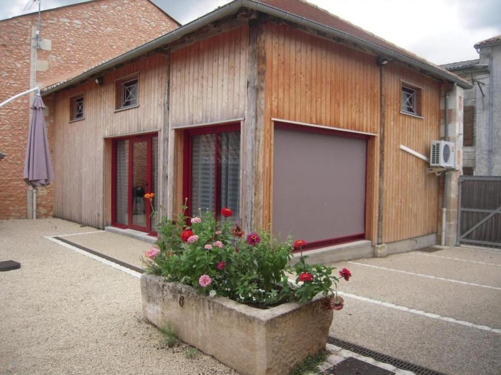 a building with a large garage with flowers in front of it at Gite du sechoir in Bouresse