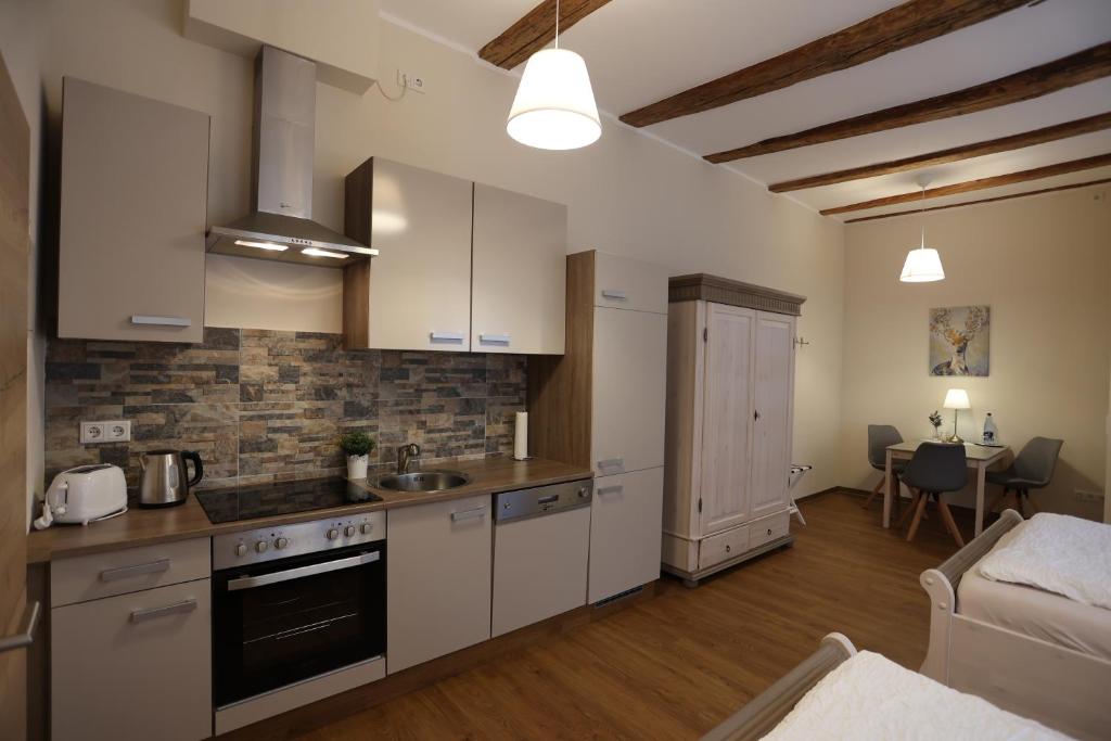 a kitchen with white cabinets and a living room at Pension Alte Scheune in Melsungen