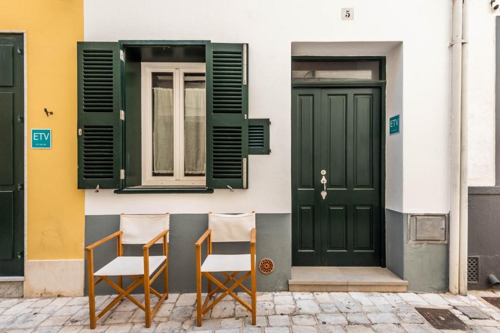 two chairs sitting in front of a building with green doors at Holiday Home Casa Sant Pere by Mauter Villas in Ciutadella