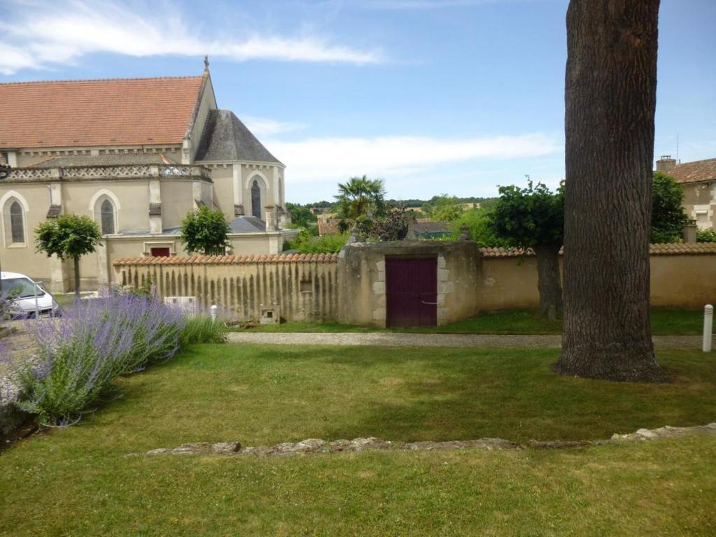 a yard with a church and a house at Les noisettes in Lhommaizé