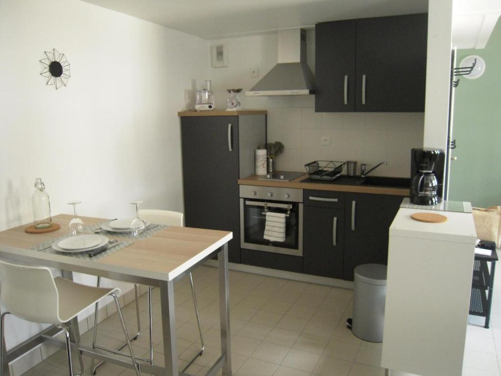 una cocina con armarios negros y una mesa con sillas en Gite du fournil, en Bouresse
