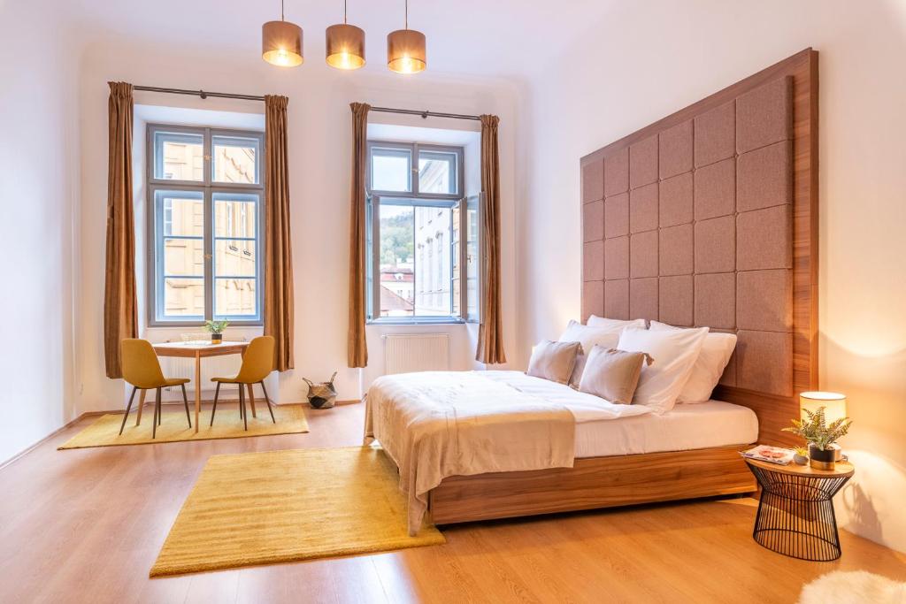 - une chambre avec un lit, une table et deux fenêtres dans l'établissement Primavera - Castle view apartments, à Prague