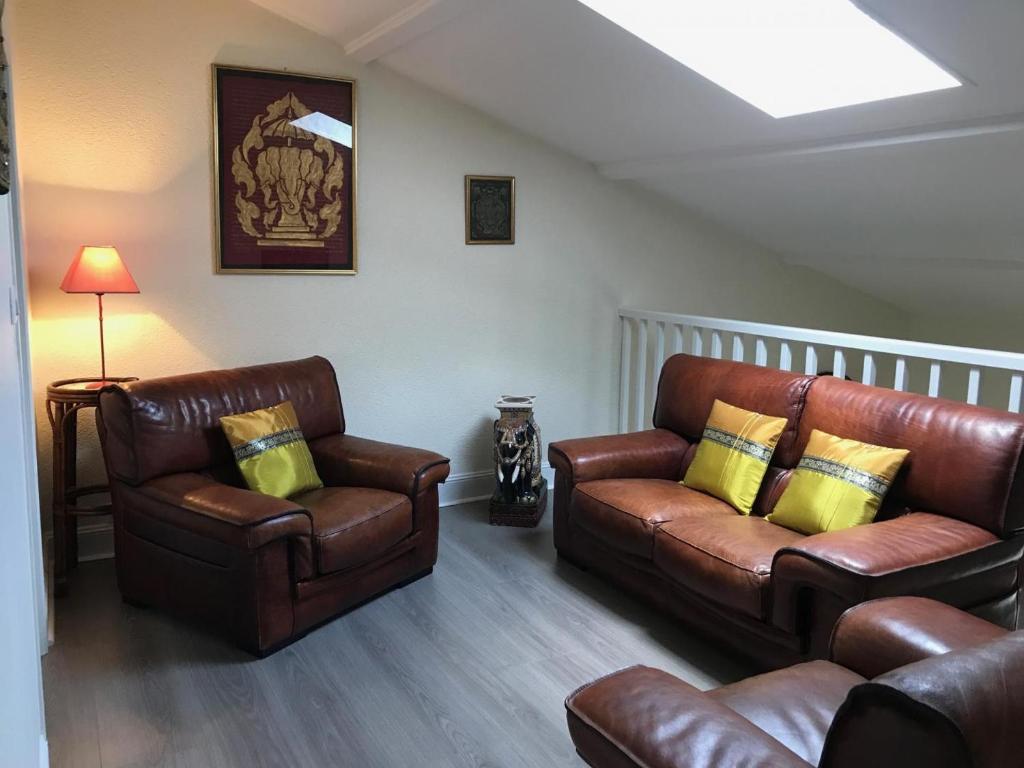 uma sala de estar com duas cadeiras de couro e um sofá em Sejour a beaubaton em Mignaloux-Beauvoir