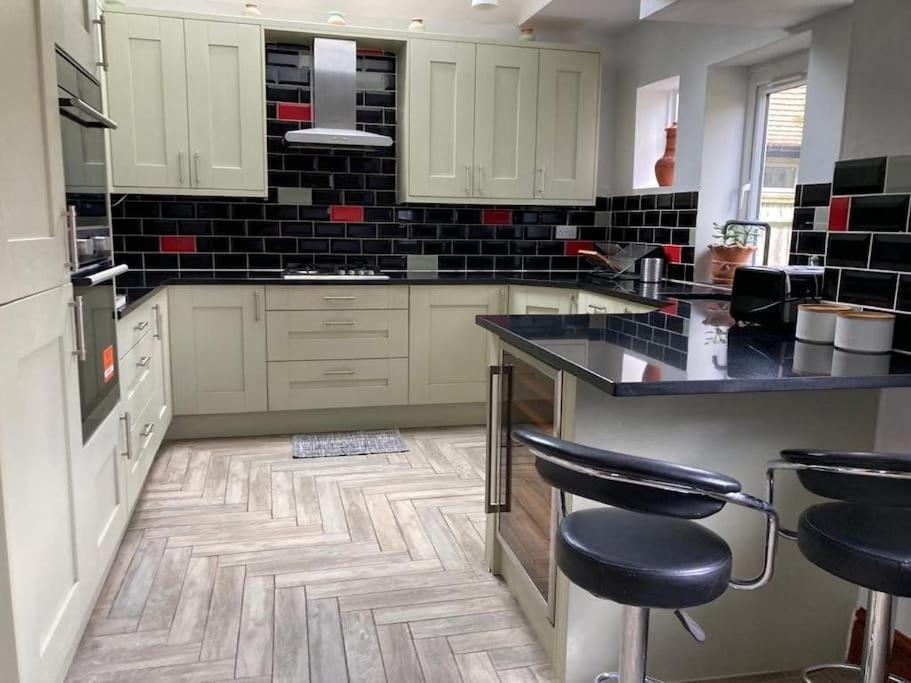 una cocina con armarios blancos y encimeras negras en Peaceful Home in Guildford Surrey UK -Free Parking, Garden, River & Waterfall, en Bramley