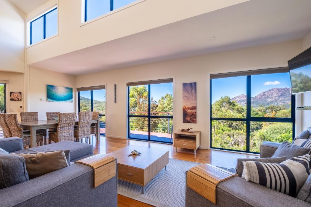 a living room with a couch and a table and windows at Haven on Bradley in Coles Bay