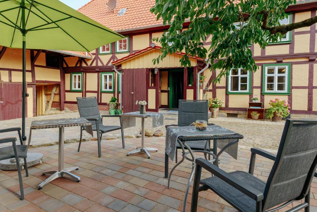un patio con mesas, sillas y una sombrilla en Wellnest am grünen Band, 